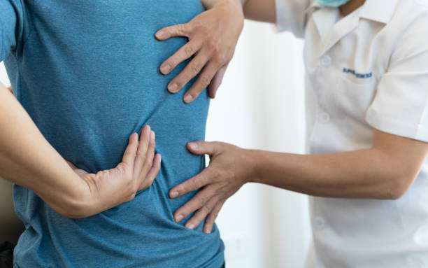 o médico está diagnosticando a dor nas costas do paciente. um homem com dor nas costas procura um médico para tratamento. - human vertebra - fotografias e filmes do acervo