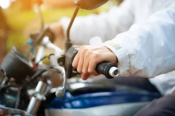 Photo of Close-up a young man holding a motorcycle handlebar and control a while driving a motorcycle.