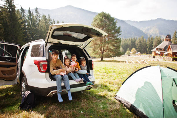 famiglia di quattro bambini all'interno del veicolo. bambini seduti nel bagagliaio. viaggiare in auto in montagna, concetto di atmosfera. - 12 23 mesi foto e immagini stock