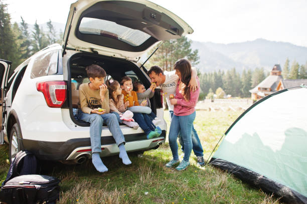 grande famiglia di quattro bambini. bambini nel bagagliaio. viaggiare in auto in montagna, concetto di atmosfera. spirito americano. - 12 23 mesi foto e immagini stock