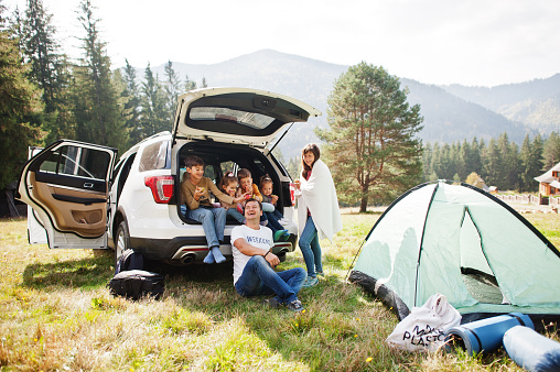 Couple with their dog relaxing in forest sitting in car trunk. Family, vacation, holidays, travel concept