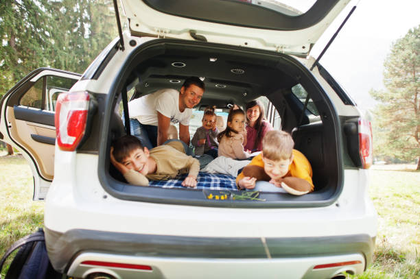 bambini di famiglia all'interno del veicolo. bambini nel bagagliaio. viaggiare in auto in montagna, concetto di atmosfera. genitori felici. - 12 23 mesi foto e immagini stock