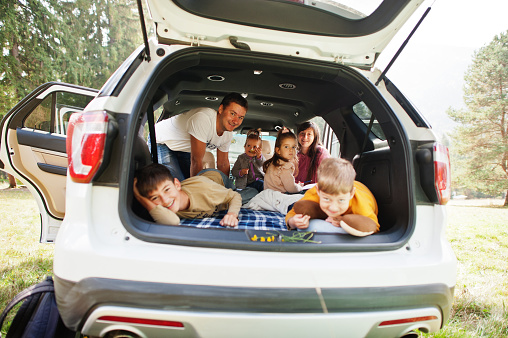 Family kids at vehicle interior. Children in trunk. Traveling by car in the mountains, atmosphere concept. Happy parents.