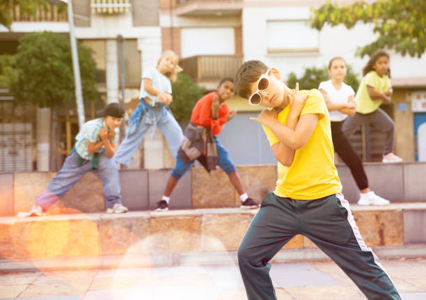 Portrait of preteen boy breakdancer dancing outdoors with children in background