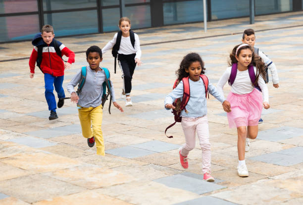 istock Group of cheerful tweenagers running in school yard after lessons 1346134495
