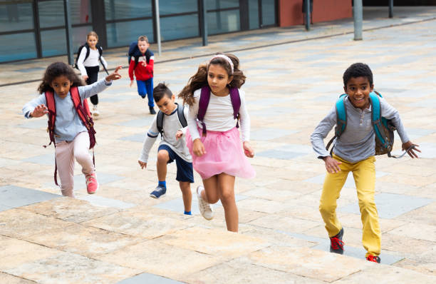 istock Group of cheerful tweenagers running in school yard after lessons 1346134503
