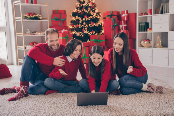 ganzkörperfoto von vier personen kind mama papa aussehen laptop sprechen vide anruf laptop mit familie wunsch fröhliche weihnachten drinnen - christmas shopping internet family stock-fotos und bilder