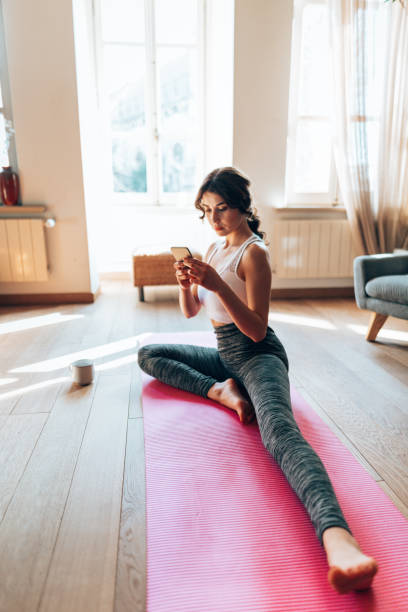 istock woman doing yoga at home and text messaging 1346137974