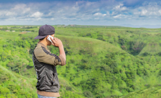Young man calling by cell phone, young man in field calling by cell phone, young man calling by phone from back with copy space