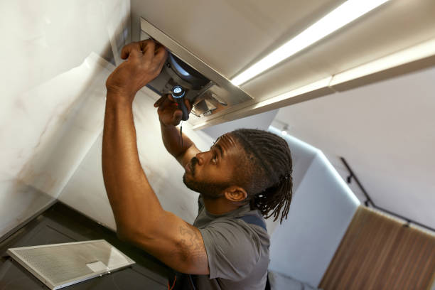 istock Closeup concentrated repairman fixing under cabinet range hood 1346139239