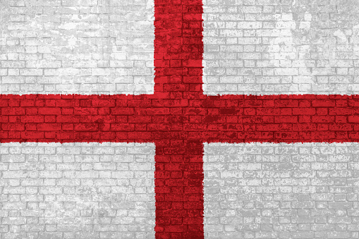 wall of bricks painted with the national England flag in 3D background. Concept of social barriers of immigration, divisions, and political conflicts in England.