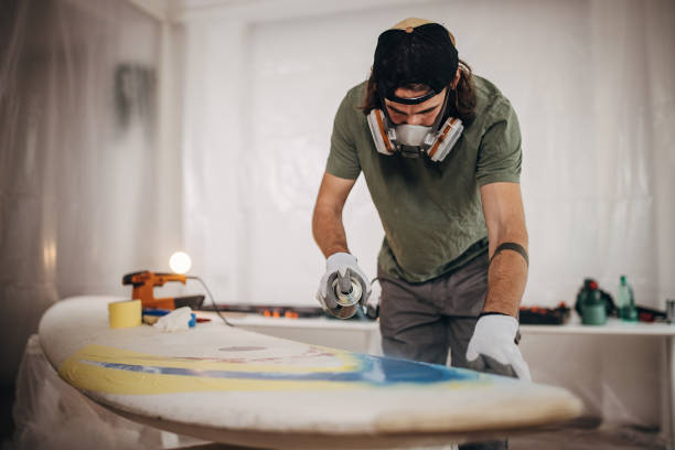 istock Man spray painting windsurfing board 1346139662