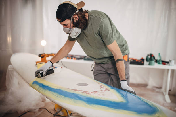 istock Man spray painting windsurfing board 1346139714