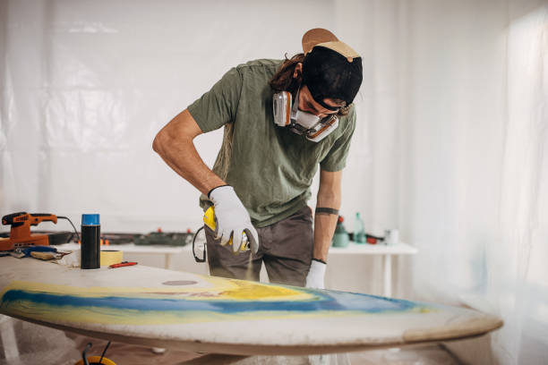 istock Man spray painting windsurfing board 1346140931
