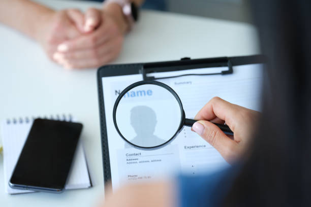 istock Employer looking at application form with magnifying glass closeup 1346141098