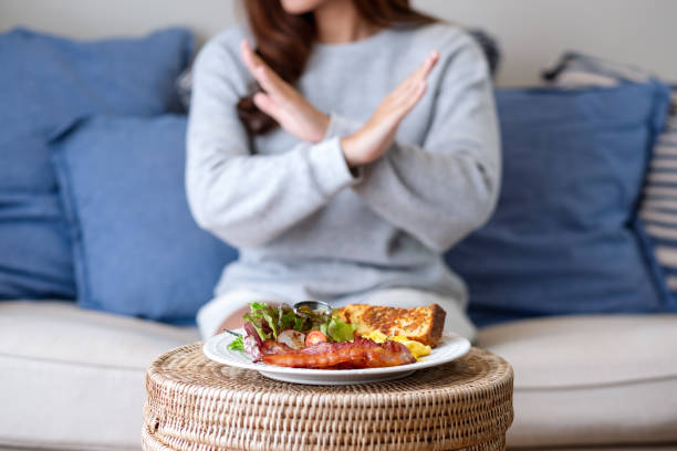женщина делает скрещенные руки, чтобы отказаться от еды на столе - dieting food rejection women стоковые фото и изображения
