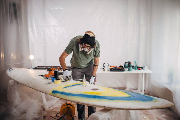 istock Man spray painting windsurfing board 1346142385