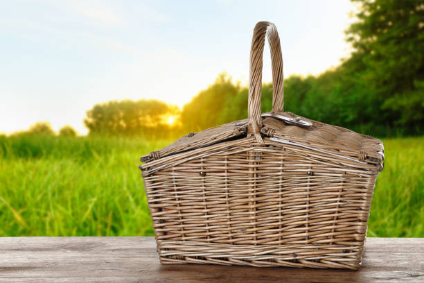 istock Wicker picnic basket on wooden table in park 1346142841