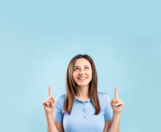 young woman over isolated blue background pointing up a great idea - pointing women cheerful front view imagens e fotografias de stock
