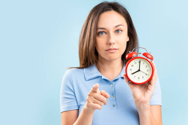 istock Young woman with alarm clock on blue background 1346142965