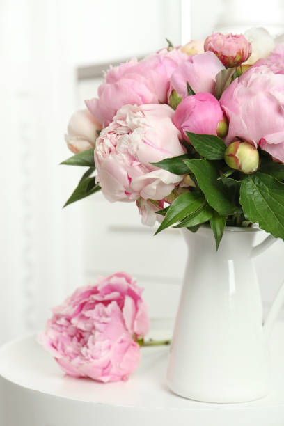 istock Bouquet of beautiful peonies in vase on white table 1346144656