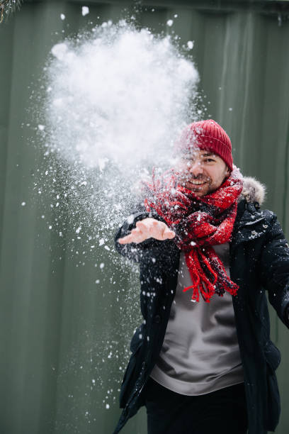 istock Playful middle age man in winter clothes throwing cloud of snow 1346145507