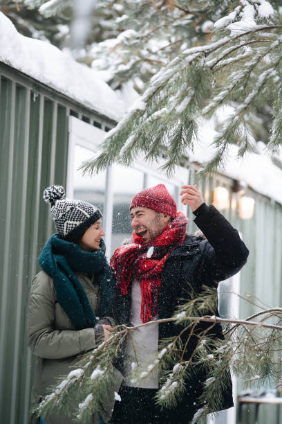 istock Cheerful couple talking, getting snow all over themselves from nearby trees 1346145511
