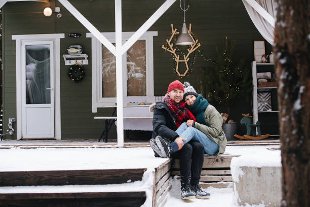 istock Middle aged couple sitting on a snowy terrace step, posing for a photo. 1346145571
