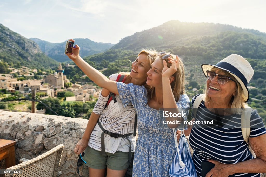 Teenage girl, mother and grandmother are sightseeing beautiful town of Valldemossa, Majorca, Spain Multi generation family sightseeing beautiful town of Valldemossa. Sunny summer day in Majorca, Spain.
Teenage girl, mother and grandmother are taking selfies. Behind them there is a magnificent view of the town of Valldemossa and the surrounding mountains - Serra de Tramuntana.
Canon R5 Vacations Stock Photo