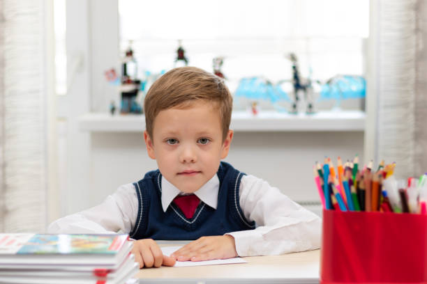 istock A cute first-grader boy in a school uniform at home while isolated at his desk makes a paper airplane during recess. Selective focus 1346147457