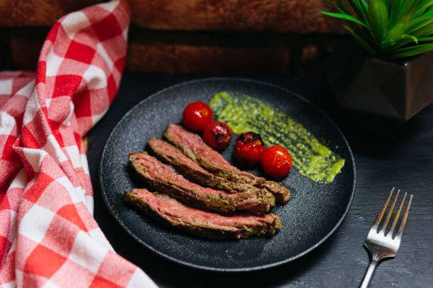 gegrilltes picanha-steak mit chimichurri-sauce und kirschtomaten auf einem schwarzen teller. - chimichurri horizontal beef steak stock-fotos und bilder