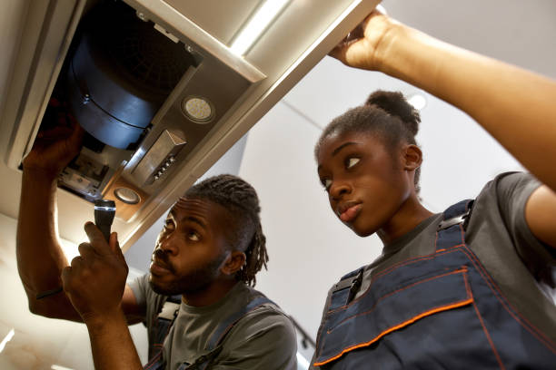 istock Experienced male electrician explaining young female apprentice how to fix kitchen exhaust problems 1346148508