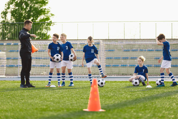 istock Group of Boys on Soccer Training Field. Young Coach Explaining Drills Rules to Kids on Football Practice. Children on School Sports Class with Trainer 1346150800