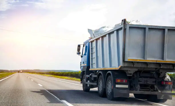 Transporting waste in a dump truck on the highway for recycling. Transportation of recyclable materials to a processing plant. Copy space for text