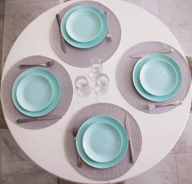 istock Kitchen table setting with turquoise plates and glasses. Cutlery on white table, interior, background 1346153213