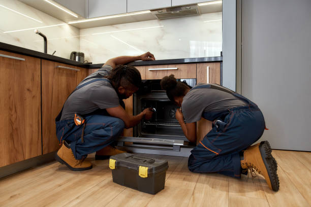 Female worker helping male partner to troubleshoot kitchen oven stock photo