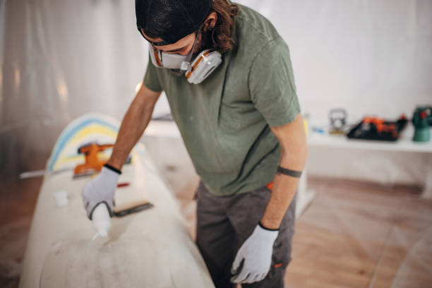 istock Man pouring wax on surfboard 1346154960