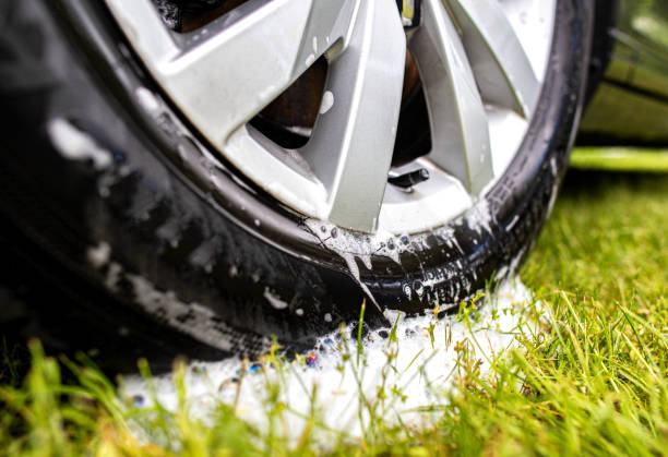 llanta de coche lavada con champú de coche y espuma sobre hierba verde. concepto de prohibición del lavado de autos en la naturaleza, violación de la ecología, multa. primer plano - wheel rim fotografías e imágenes de stock