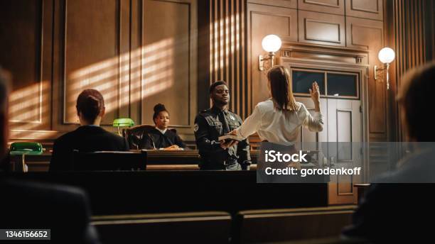 Law And Justice Court Case Witness Solemnly Swears That The Evidence She Shall Give Shall Be The Truth And Nothing But The Truth Before Testifying To Lawyers And Judge In Courthouse Stock Photo - Download Image Now