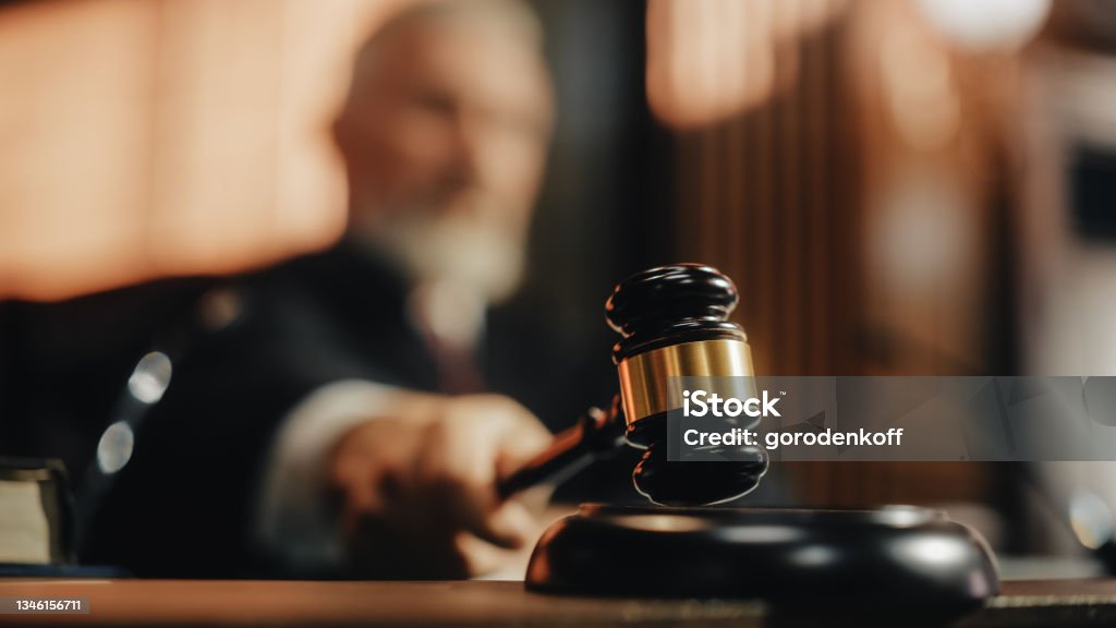 Court of Law and Justice Trial Session: Imparcial Honorable Judge Pronouncing Sentence, striking Gavel. Focus on Mallet, Hammer. Cinematic Shot of Dramatic Not Guilty Verdict. Close-up Shot. Courthouse Stock Photo