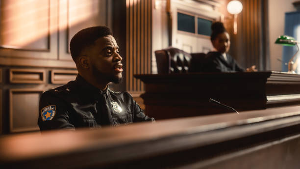 Court of Law and Justice Trial Stand: Portrait of Black Policeman Witness Giving Testimony to Judge, Jury. African American Officer Providing Evidence. Law Enforcement Agent in Courthouse. Court of Law and Justice Trial Stand: Portrait of Black Policeman Witness Giving Testimony to Judge, Jury. African American Officer Providing Evidence. Law Enforcement Agent in Courthouse. witness stock pictures, royalty-free photos & images