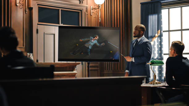 Court of Law Trial in Session: Portrait of Charismatic Male Public Defender Showing Dead Man on TV Screen to Judge and Jury. Attorney Lawyer Protecting Client, Presenting Case. Court of Law Trial in Session: Portrait of Charismatic Male Public Defender Showing Dead Man on TV Screen to Judge and Jury. Attorney Lawyer Protecting Client, Presenting Case. Personal Injury Trial stock pictures, royalty-free photos & images