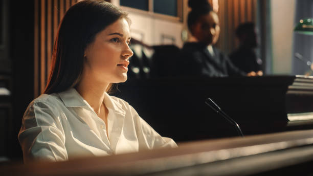 court of law and justice trial: portrait of beautiful female witness giving evidence to prosecutor and defence counsel, judge and jury listening. dramatic speech of empowered victim against crime. - violence domestic violence victim women imagens e fotografias de stock