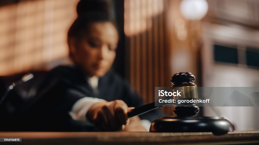 Court of Law Trial in Session: Honorable Female Judge Pronouncing Sentence, striking Gavel. Focus on Mallet, Hammer. Cinematic Shot of Dramatic Not Guilty Verdict. Close-up Shot. Judge - Law Stock Photo