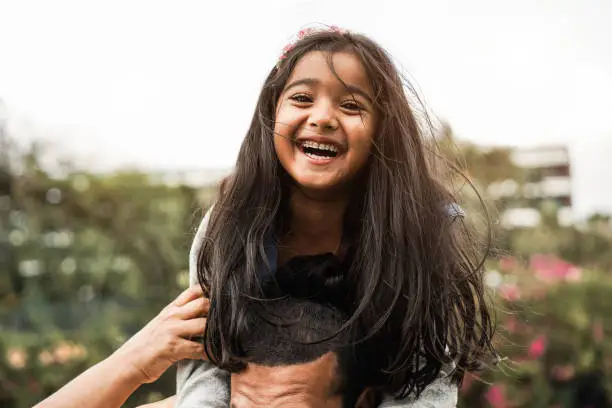 Photo of Happy indian father having fun with her daughter outdoor - Focus on girl face