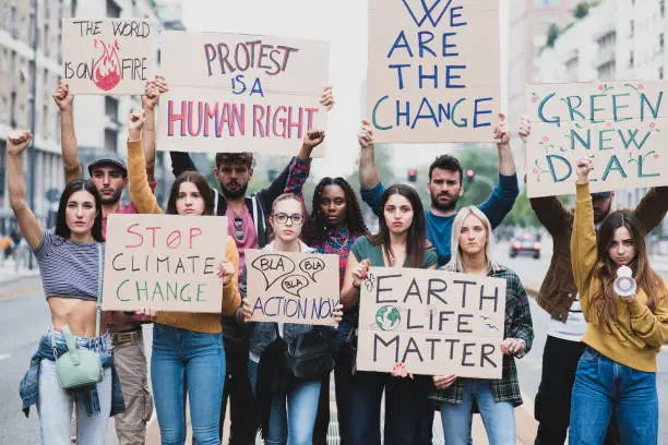 Photo of People protesting with placards and posters on global strike for climate change, young students marching for world health