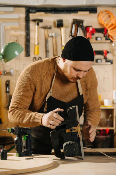 istock Keen carpenter in a watch cap in a big workshop. Checking electric plane 1346161042