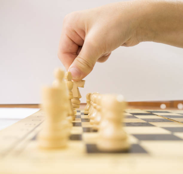 istock One person arranges white chess pieces on a wooden board. Brain-developing games 1346162387