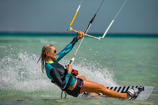 Kite surfer woman rides with kiteboard  in transition