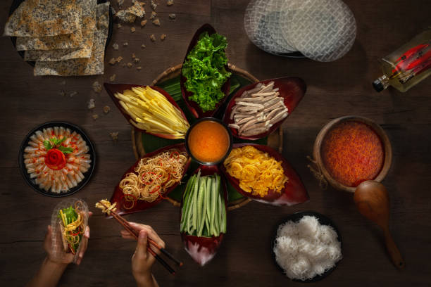 Lau. Hot pot with pork, banana flowers, mango, salted fish, scrambled eggs, rice noodles - Vietnamese cuisine. Female hands collect ingredients in a cake